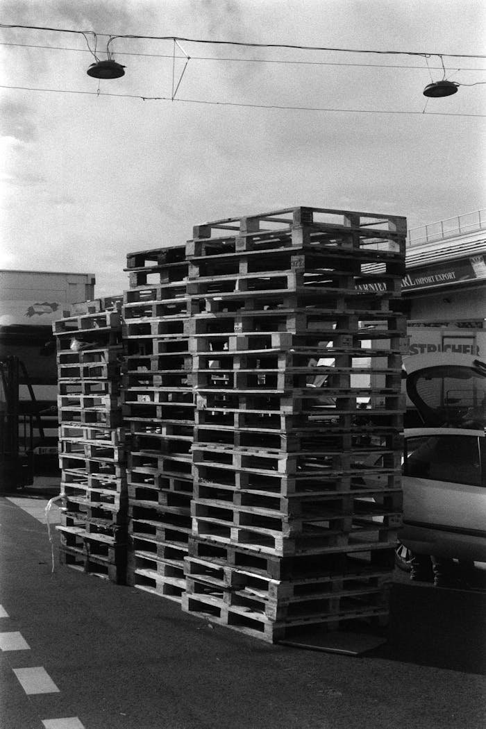 Black and white photo of stacked wooden pallets in an industrial zone in France.